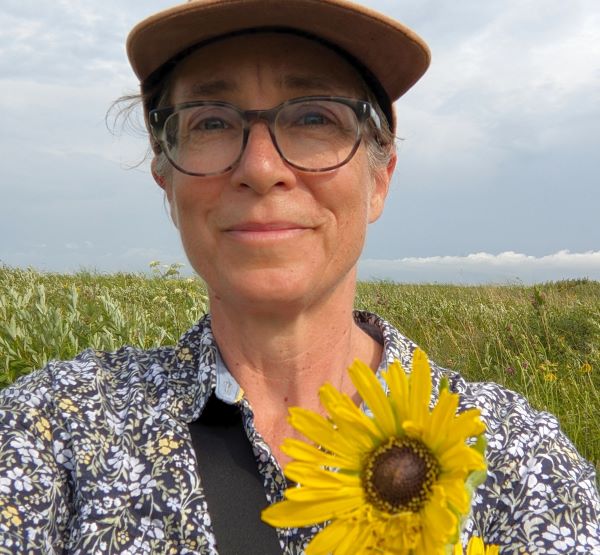 Laura Fischer Walter standing in a prairie with a compass plant flower