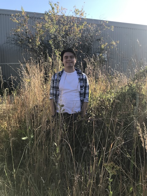 Photo of Ethan Dickey in tall grass by Tallgrass Prairie Center building