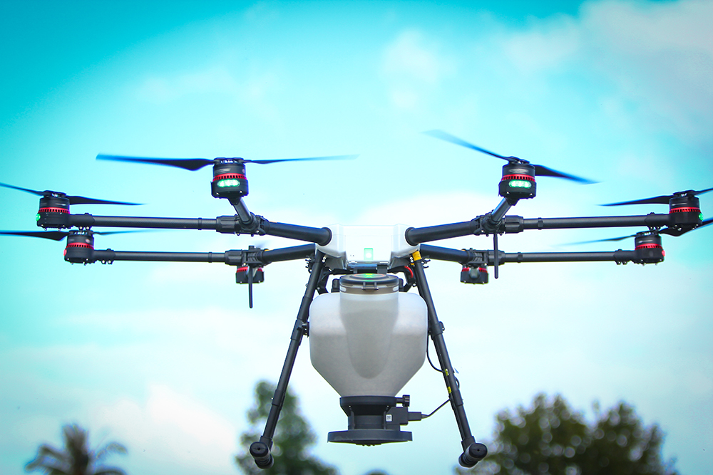 A drone flies over a roadside to drop seed.