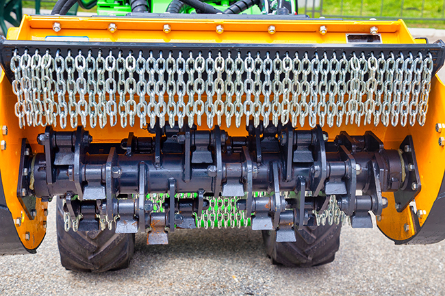 A view of a rotary forestry mower with chains, spinning blades, and other mechanical components.