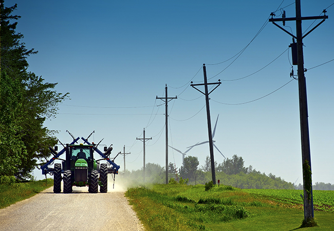 An agricultural tractor driving down a rural gravel road.