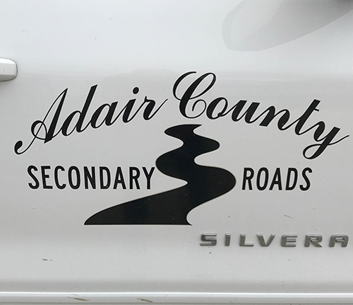 The Adair County Secondary Roads logo on the side of a truck.
