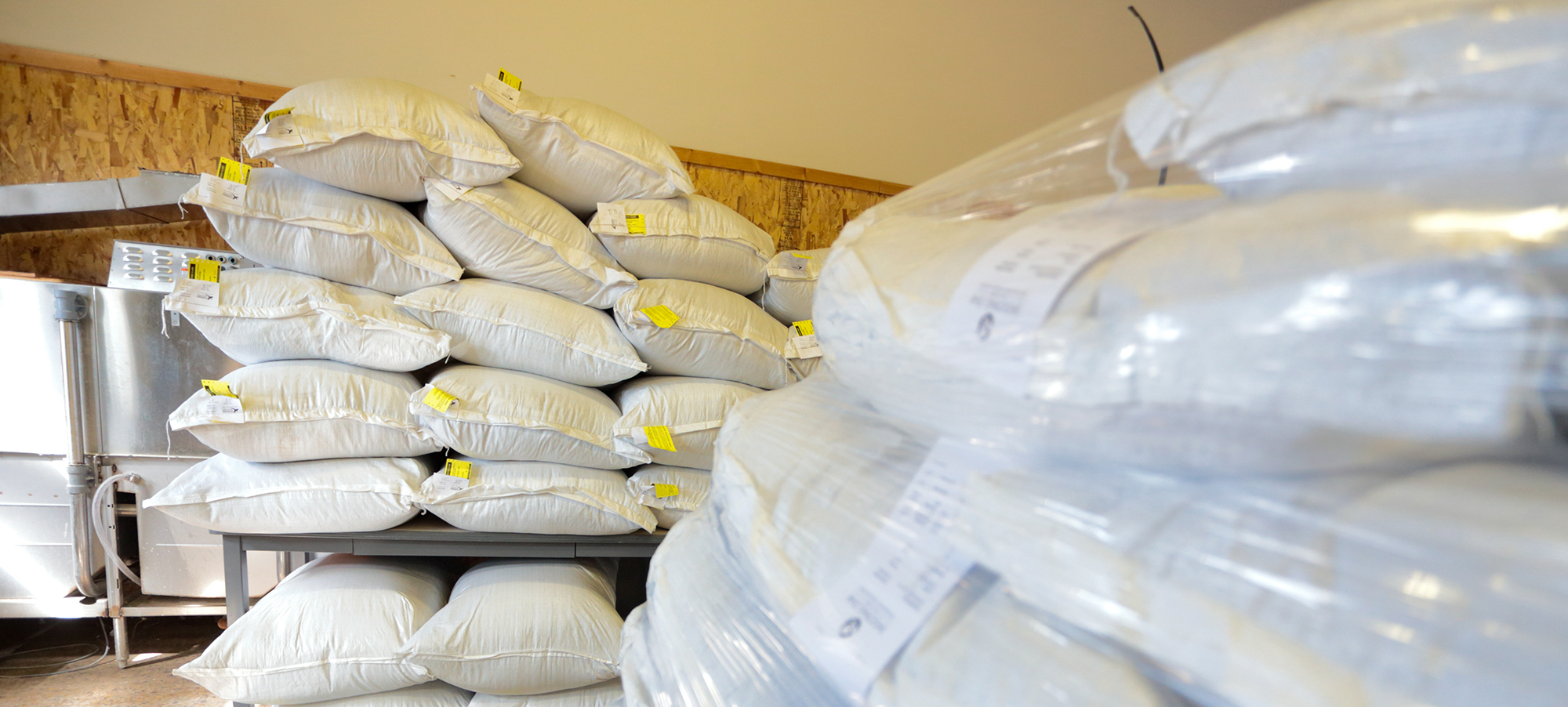 Bags of seeds stacked up in a storage room.