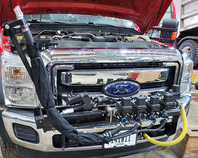 The front of a truck with a spray system mounted to the bumper.