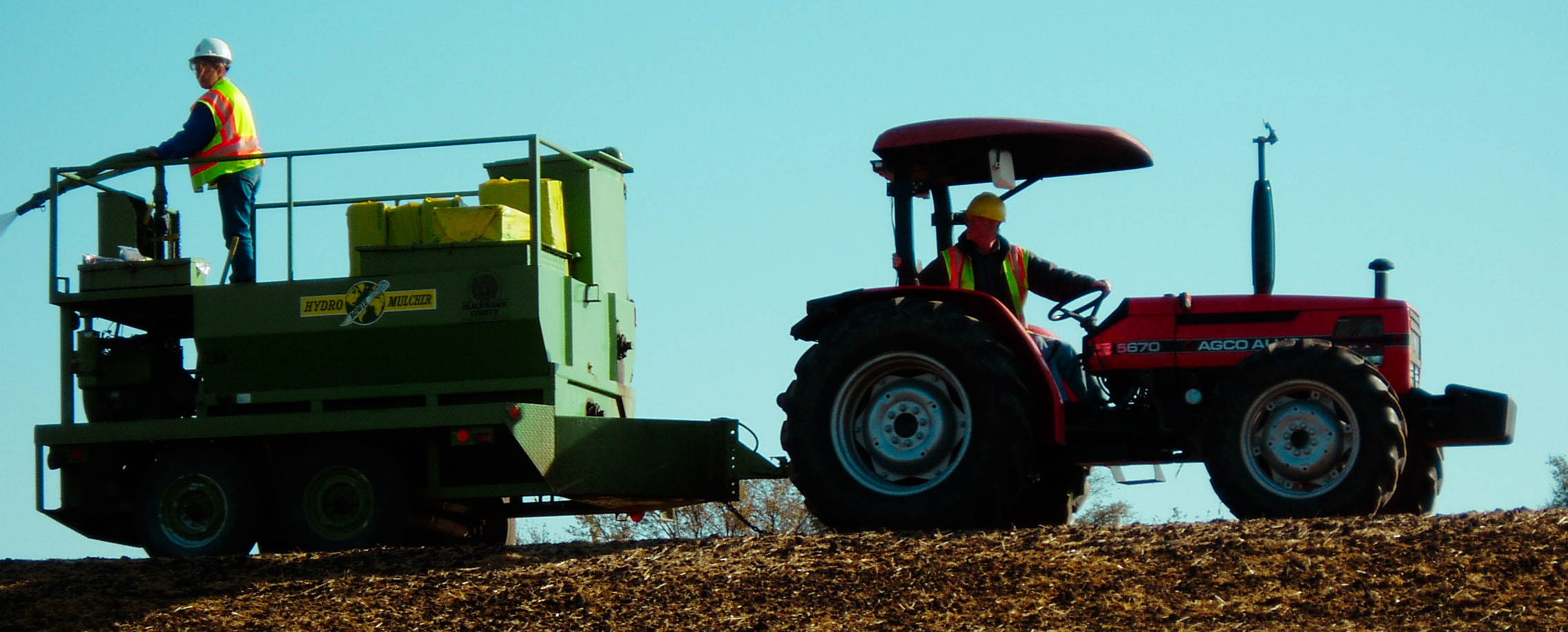 Roadside management staff use a tractor and a trailer hydroseeder to manage roadside vegetation. 