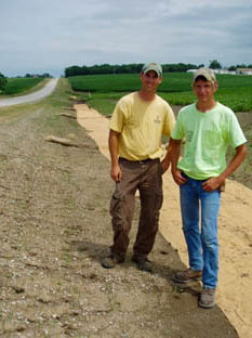 Two roadside management staff stand in a roadside with erosion control measures.