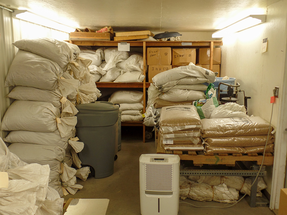 Bags of seed stored in a small room with a dehumidifier.