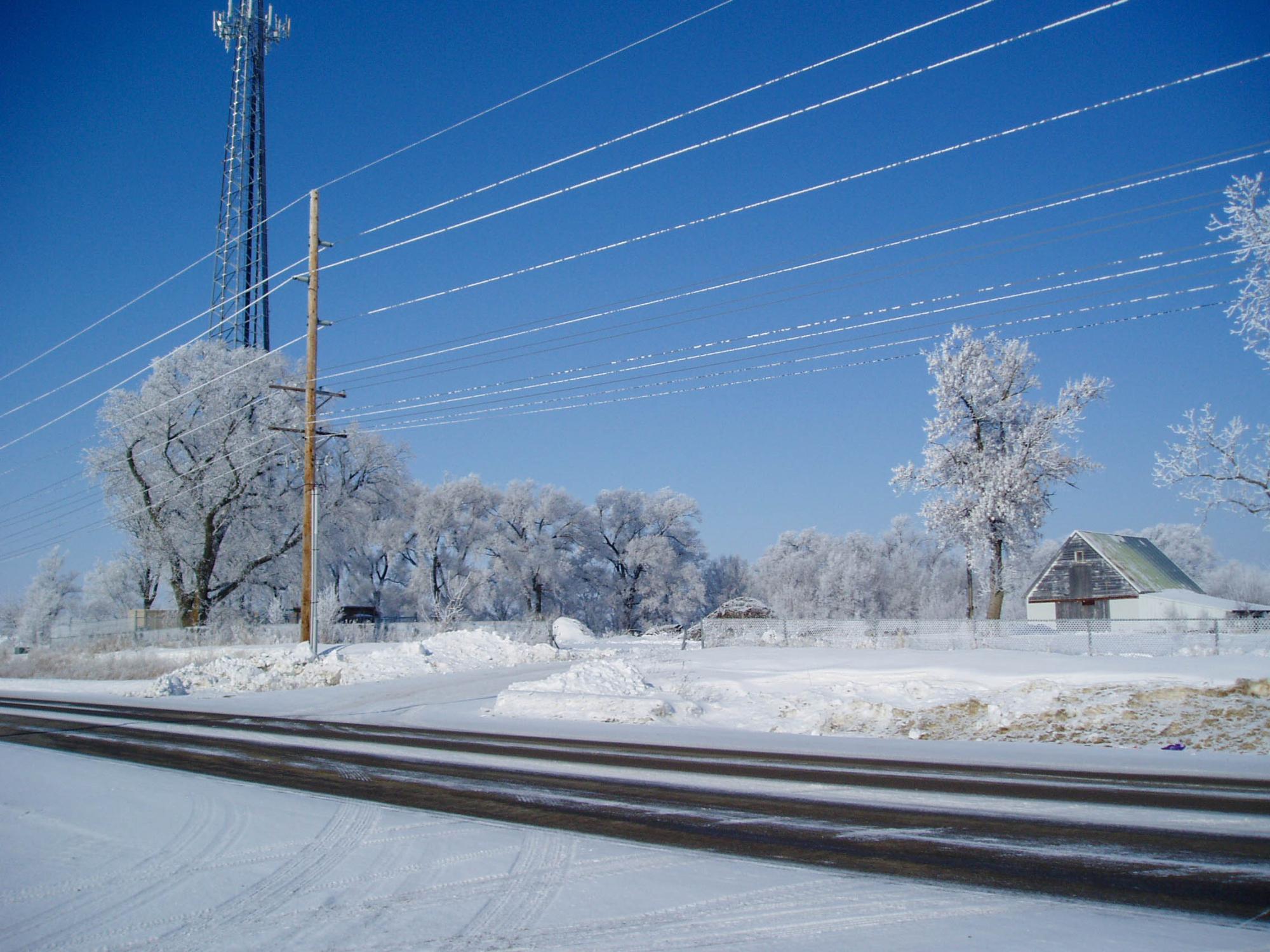 A plowed two-lane road traverses a snow-covered landscape.